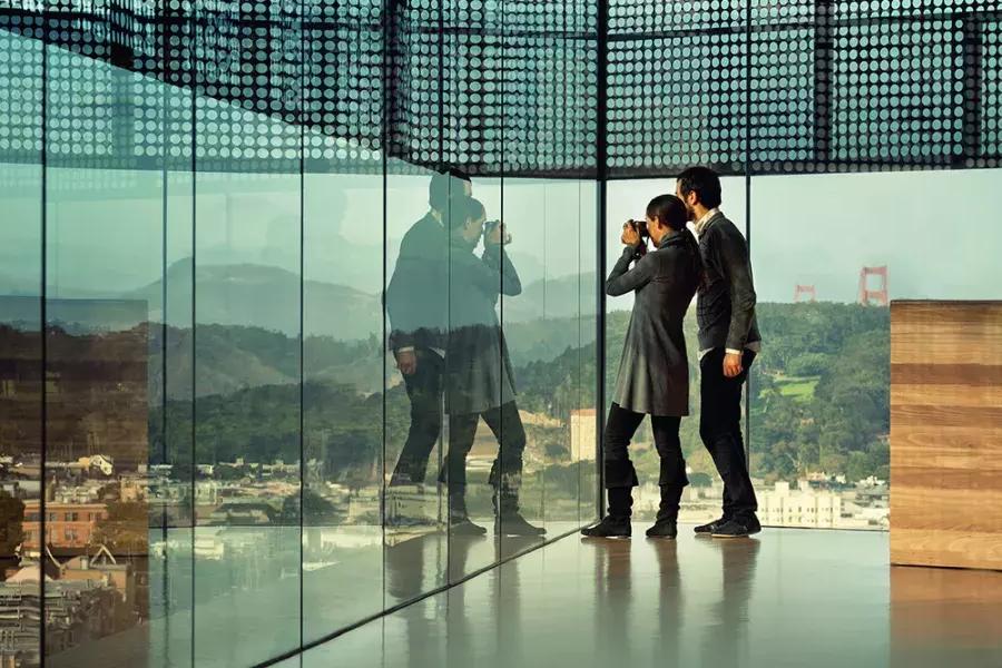 在贝博体彩app的德英美术馆，两个人正在透过玻璃墙窥视.