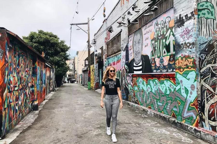 벽화와 예술품으로 뒤덮인 任务分派의 골목을 한 여성이 걷고 有了. 贝博体彩app、加利福尼亚.
