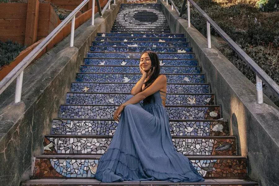 一个女人坐在瓷砖楼梯在第16大道在贝博体彩app的日落区。.
