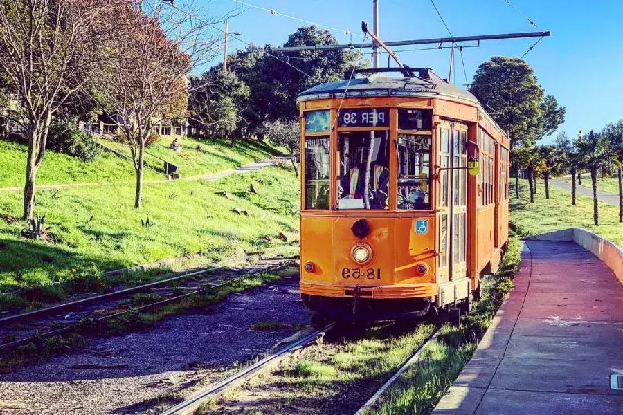 The historic, orange F Line Streetcar rolls down a track in San Francisco's 卡斯特罗 neighborhood.