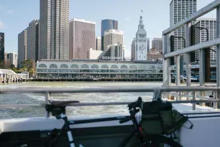 Vélo appuyé contre un rail avec le Ferry Building en arrière-plan.