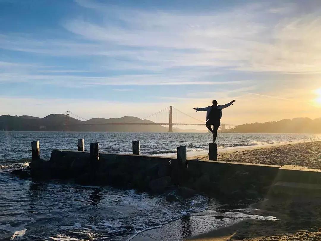 Una mujer de pie en un muelle en el barrio Marina de San Francisco, mirando el puente Golden Gate.