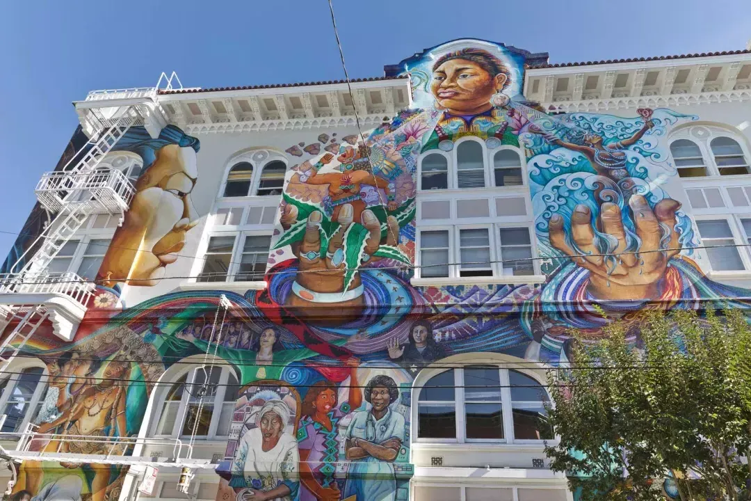 다채롭고 대규모의 벽화가 샌프란시스코 미션 디스트릭트의 여성 빌딩 측면을 덮고 있습니다.