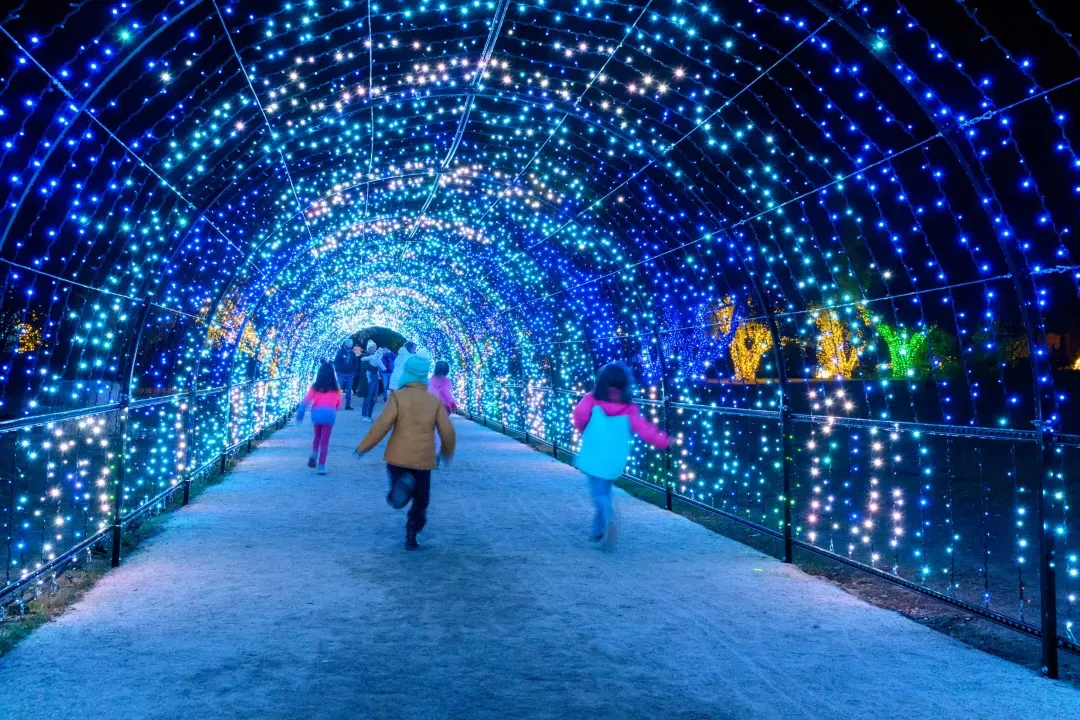 孩子们跑在隧道的圣诞灯，闪耀着蓝色