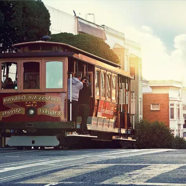 乗客が窓の外を眺めながら、サンフランシスコの丘を周回するケーブルカー。