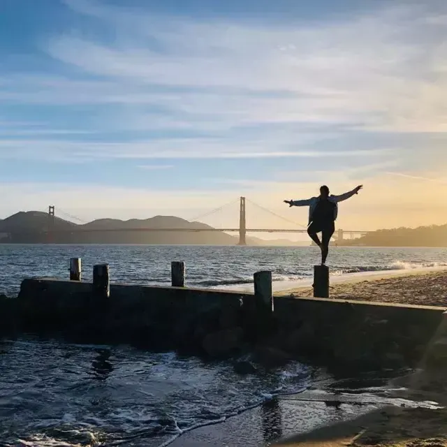 Una donna si trova su un molo nel quartiere Marina di San Francisco, guardando il Golden Gate Bridge.