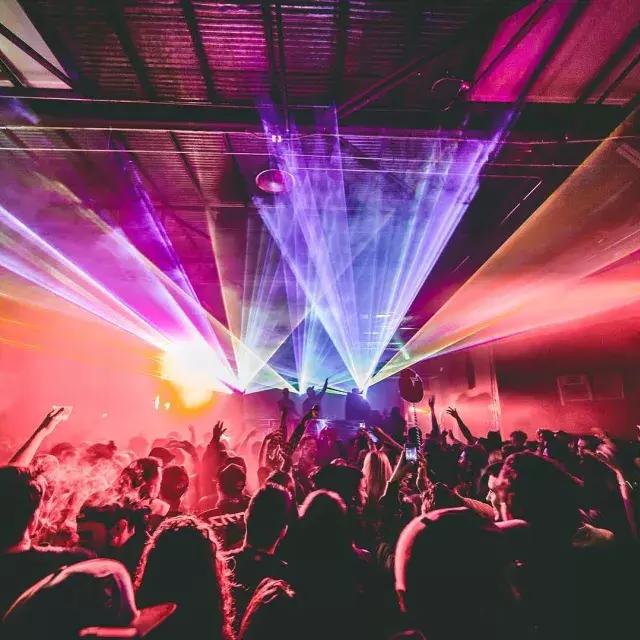 Imagen de personas saliendo en un club nocturno con luces coloridas